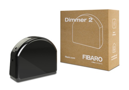 Inteligentny moduł natężenia światła Fibaro w czarnej obudowie leży na białym tle wraz z pudełkiem.